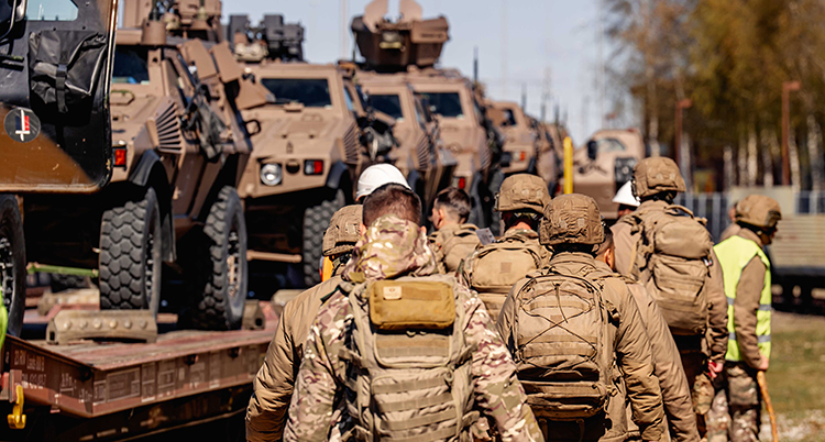 Soldater i bruna kläder och fordon som står på vagnar.