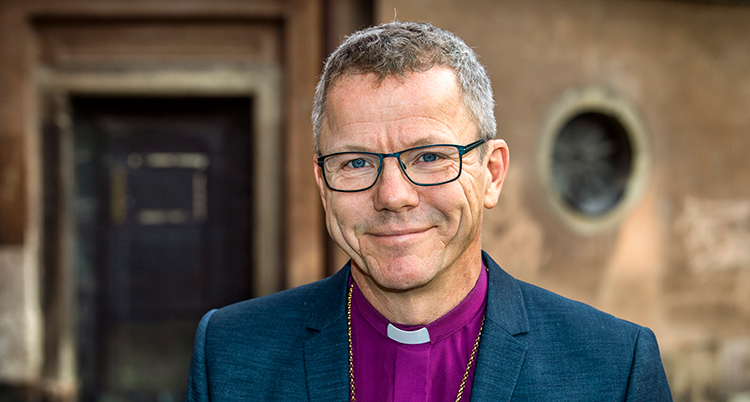 Han ler och har en vit krage i sin skjorta.