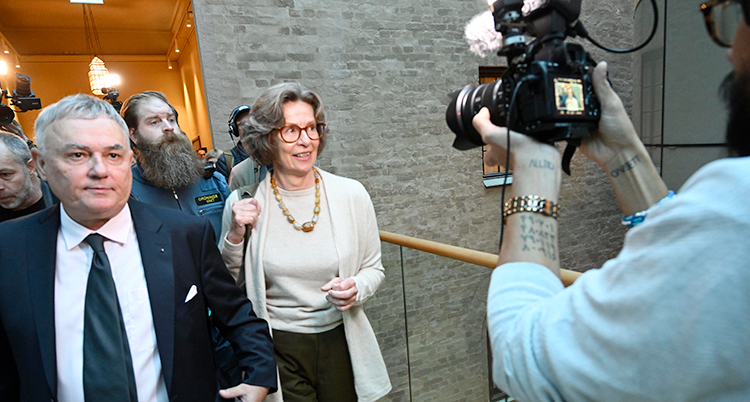 Hon är i domstolens hus på väg mot en rättegång. Hon går tillsammans med flera andra. Hon blir fotad och filmad.