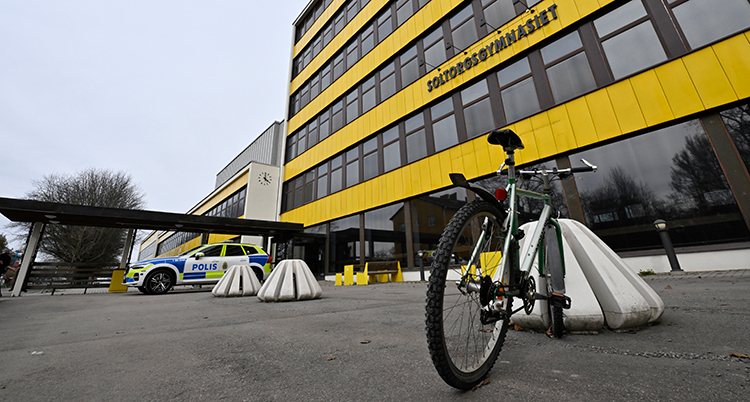 En cykel utanför en skola. En polisbil står längre bort.