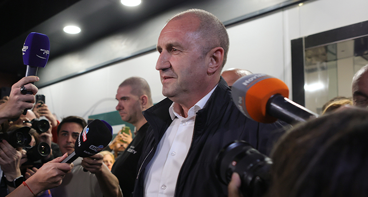 Han pratar med journalister som sträcker fram mikrofoner.