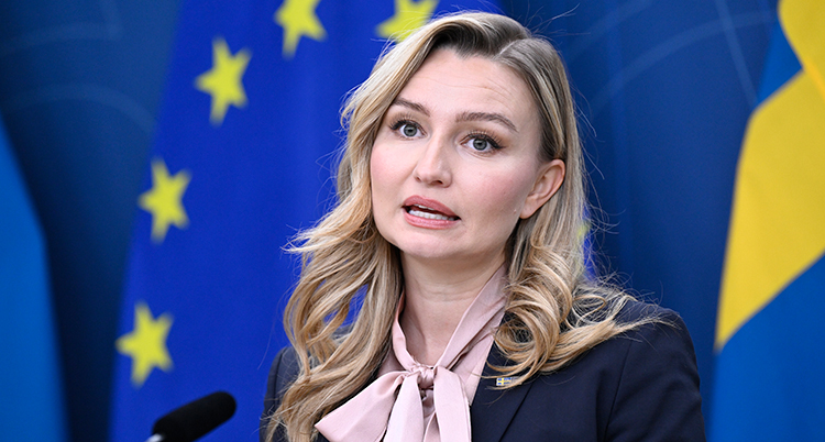 Hon pratar på ett möte med journalister. Bakom henne syns EUs och Sveriges flaggor.