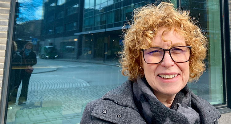 Ett porträtt av en kvinna med glasögon och lockigt hår.