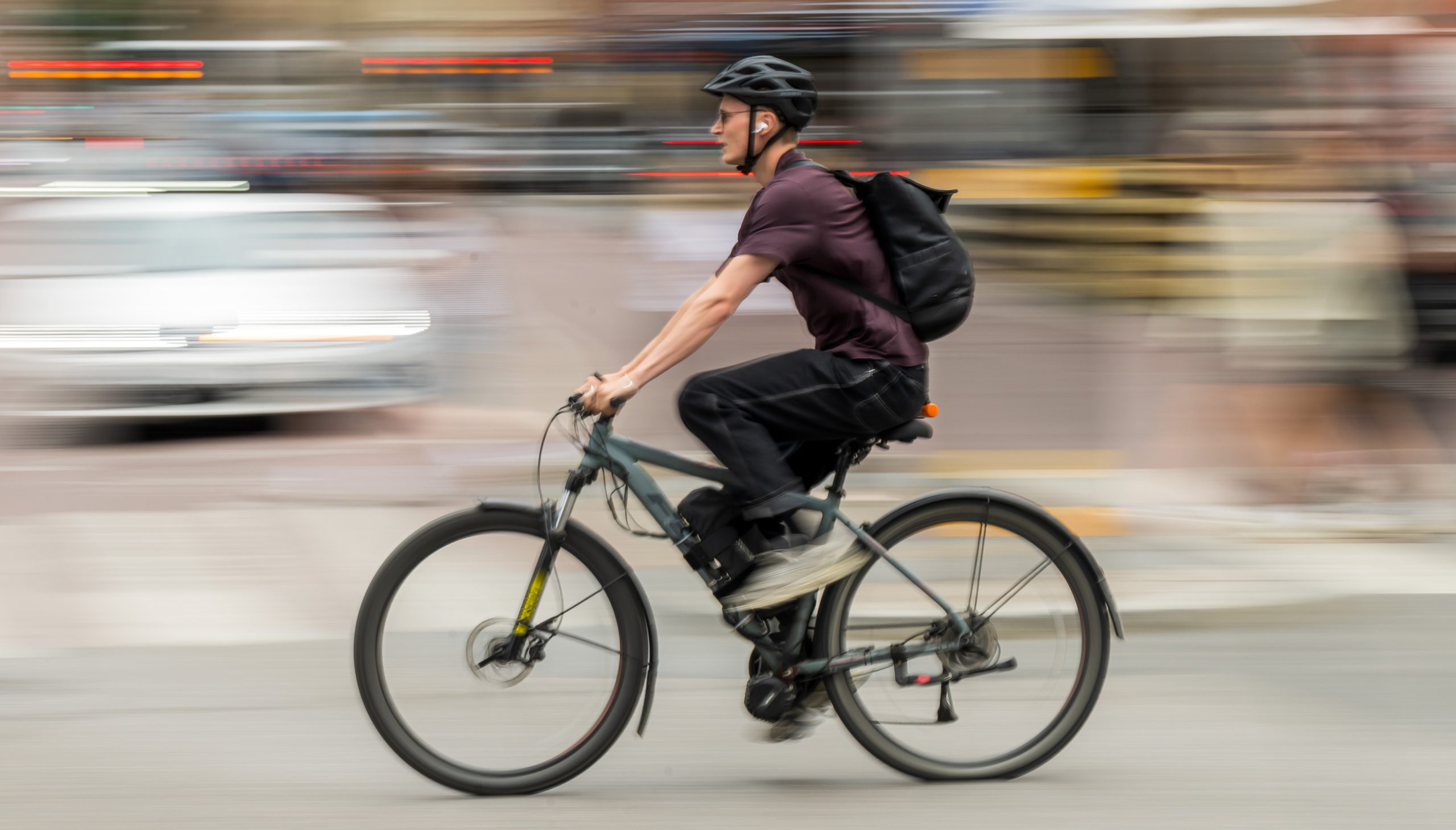 En man med hjälm och ryggsäck cyklar.