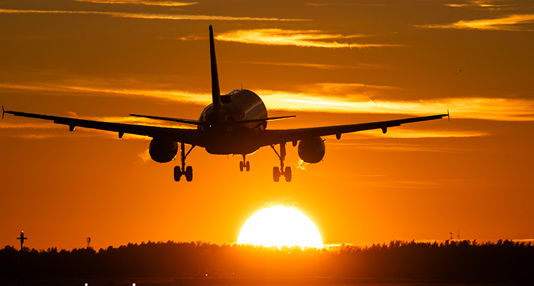 Ett flygplan i luften. Solen går ner.