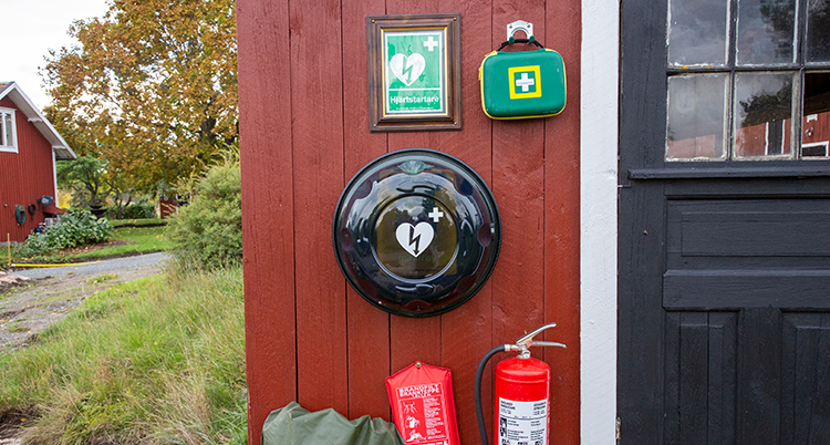 En grön väska och en grön skylt syns på en röd husvägg.