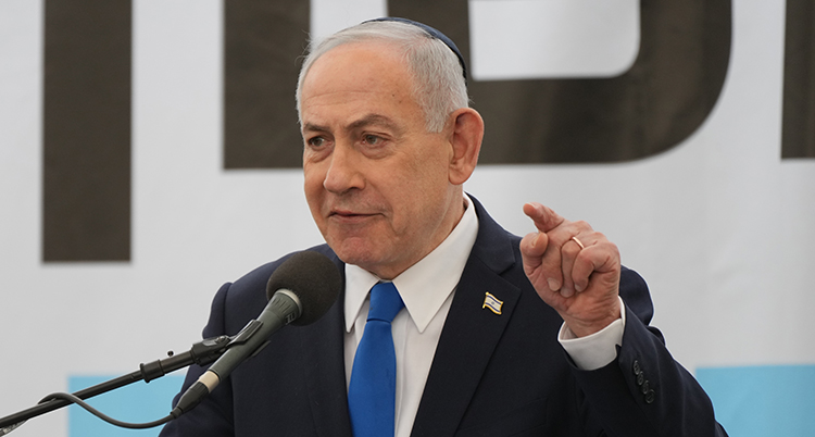 Han pratar i en mikrofon och pekar med ett finger.