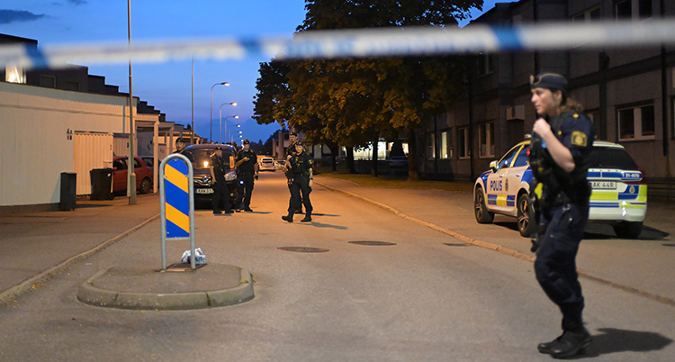 De står på en mörk gata. Polisernas band spärrar av gatan.