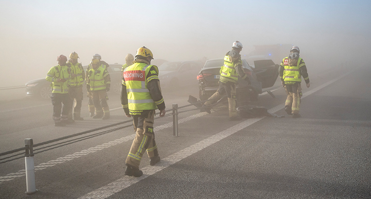 De jobbar på en väg med vajer. Det syns bilar som står stilla. Luften är disig.