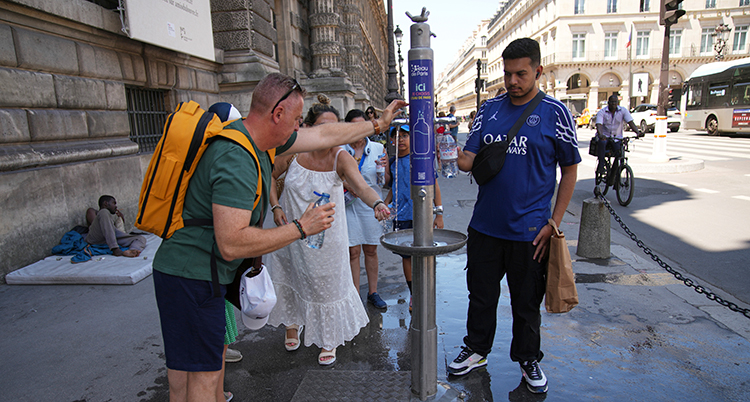 Folk dricker vatten ur en kran i staden.