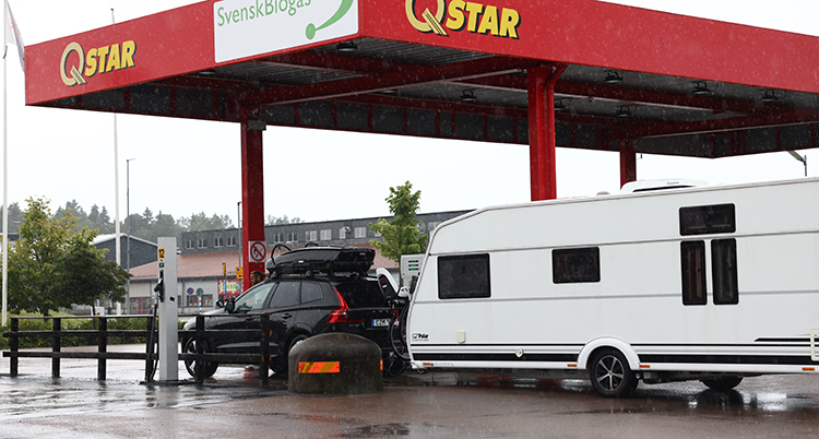 En bil med husvagn tankar vid en mack.
