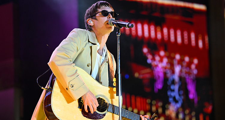 Han håller en gitarr och sjunger.