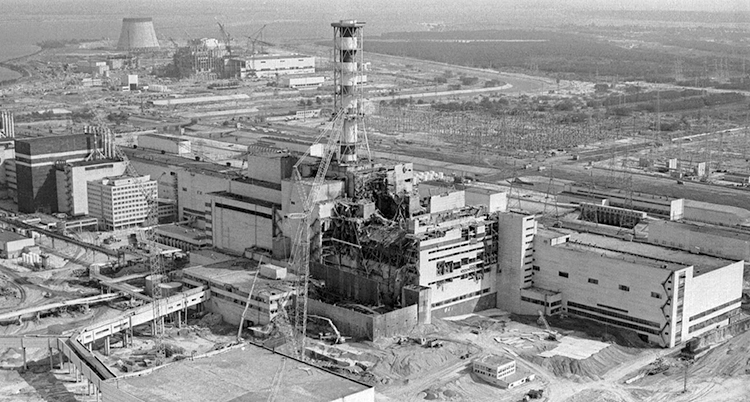 En svartvit bild på det skadade kärnkraftverket. Bilden är tagen från en helikopter.