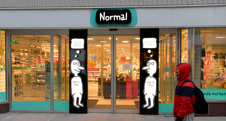 En person går förbi ingången till butiken. Affärs logga är en tecknad gubbe med lång näsa.