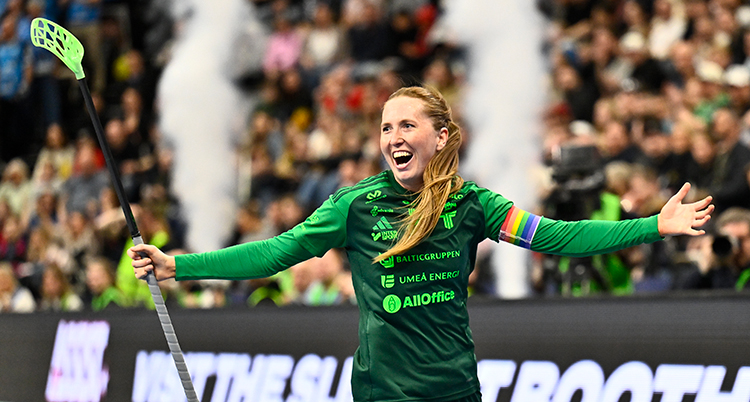 Hon är glad och sträcker armarna rakt ut. Hon har en klubba i ena handen.