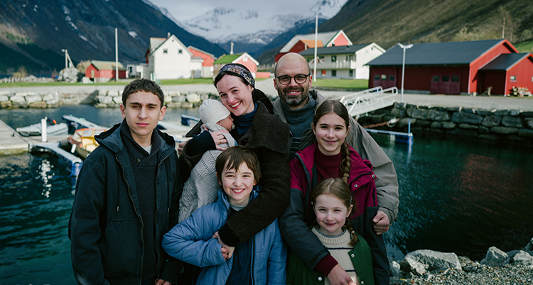 Två vuxna står med fyra barn. Bakom dem syns en fjord.
