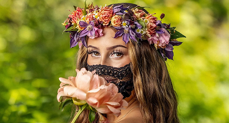 Felicia med blommor i håret och en mask över ansiktet.
