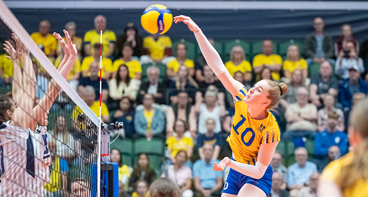 Hon hoppar upp och smashar till bollen i en match i volleyboll.