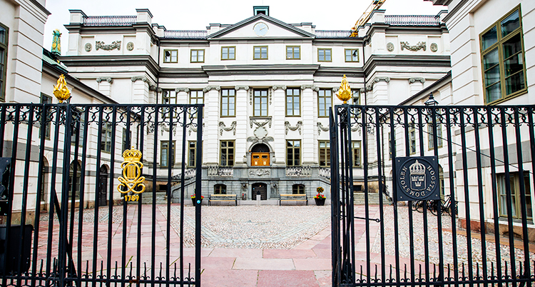 Ett stort och gammalt och vitt hus med grindar framför.