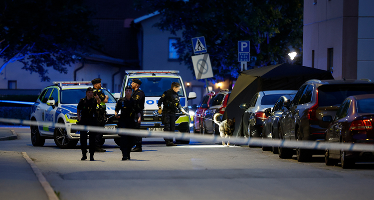 Poliser och polisbil på en avspärrad plats.