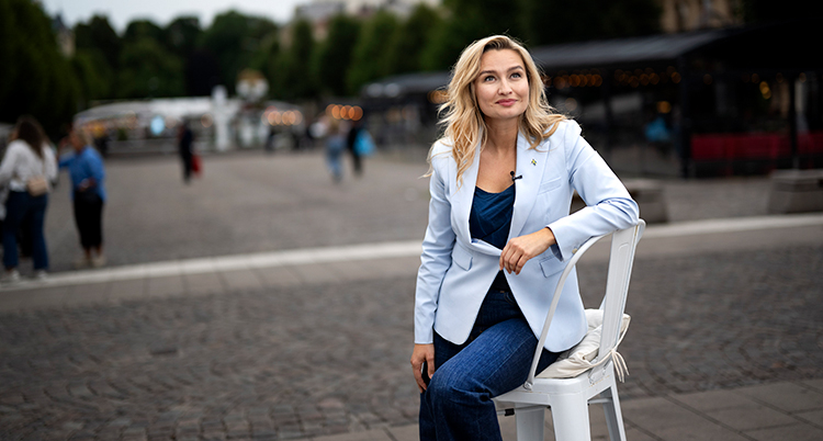 Hon sitter på en stol som står på ett torg.