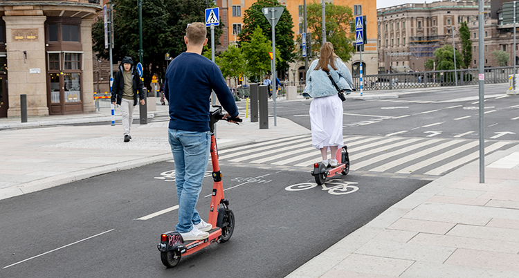 En man och en kvinna kör varsin elsparkcykel på en cykelbana i Stockholm.