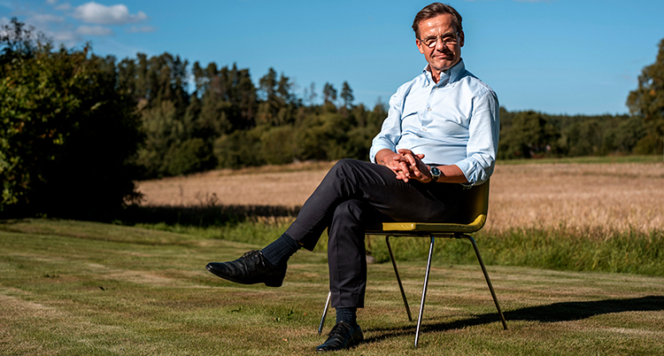 Han sitter på en stol på en gräsmatta.