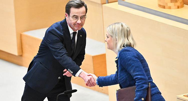De skakar hand med varandra inne i riksdagens stora sal.