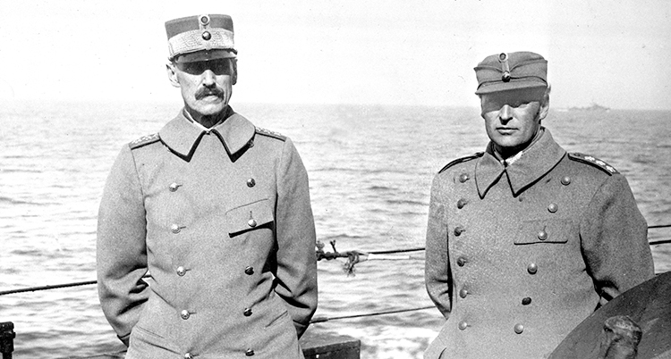 Två män i militärkläder står på en båt. De ser allvarliga ut.