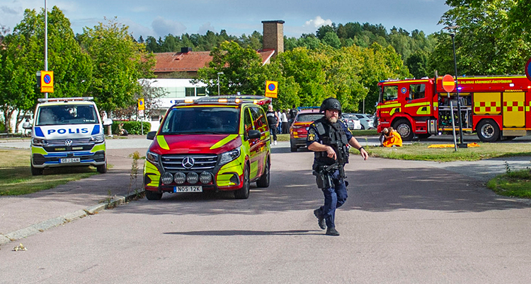 En polis går framför bilar från polis och brandkår.