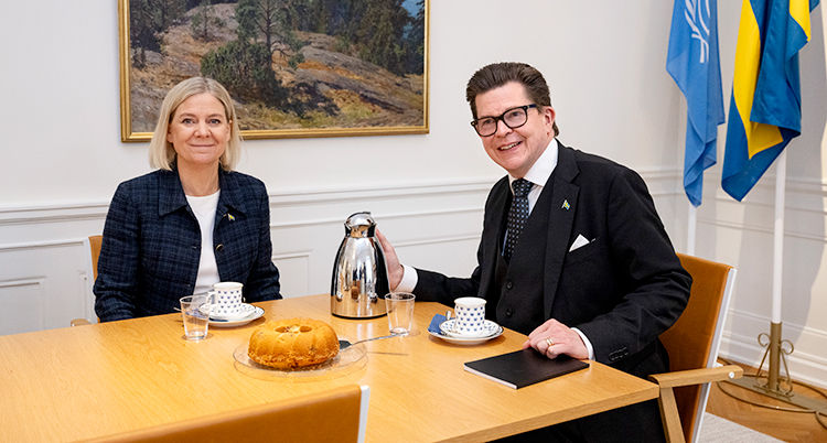 De sitter vid ett bord med kaffe och kaka.