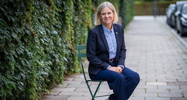 Hon sitter på en stol på en trottoar.