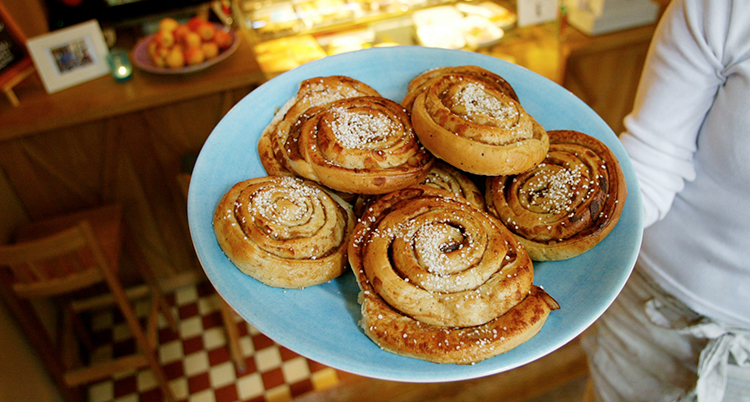 En person håller i ett fat med kanelbullar.