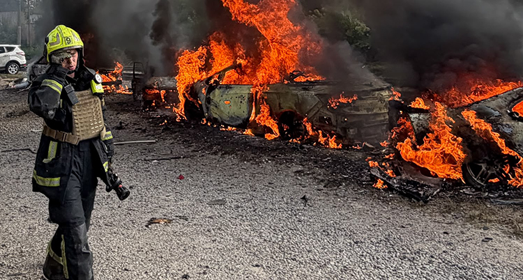 En brandman går förbi en brinnande bil.
