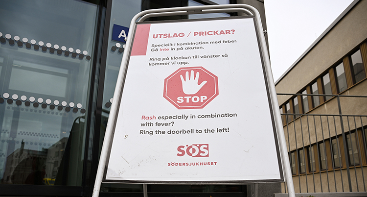En skylt med en stor hand som stoppar folk från att gå in om de har röda prickar på kroppen.