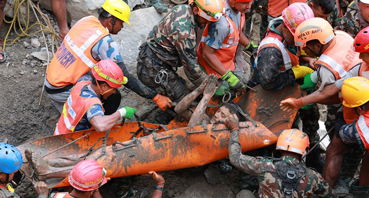 En man på en lerig bår med räddningsarbetare runt omkring sig.