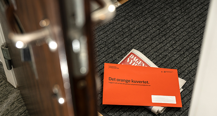 Ett orange kuvert ligger på en matta i en hall.