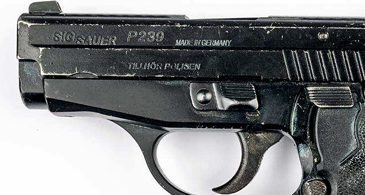 En nära bild på en pistol. Det står Tillhör polisen på pistolen.