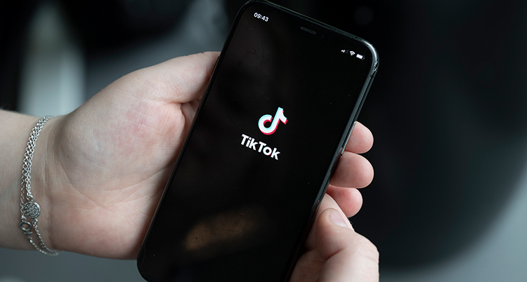 En hand håller i en mobil som visar Tiktok.