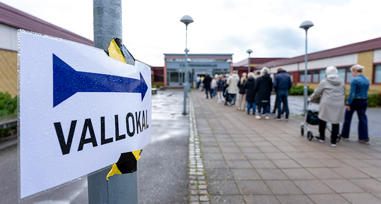 Människor står i kö utanför en skola.