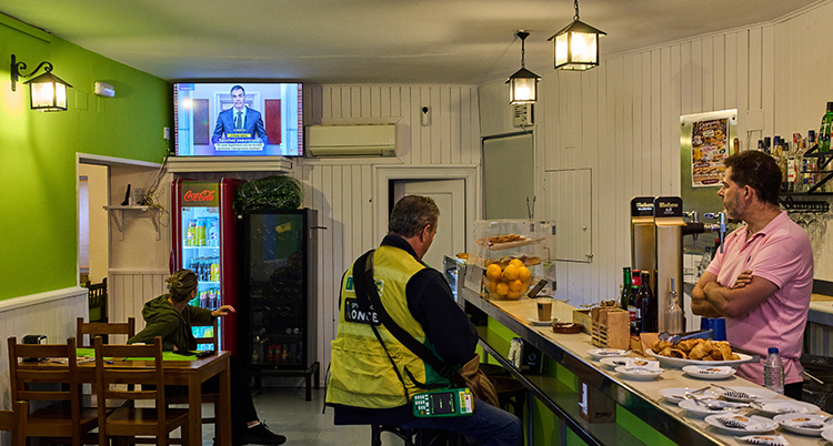 Ledaren är på tv. Folk i en bar lyssnar och tittar.