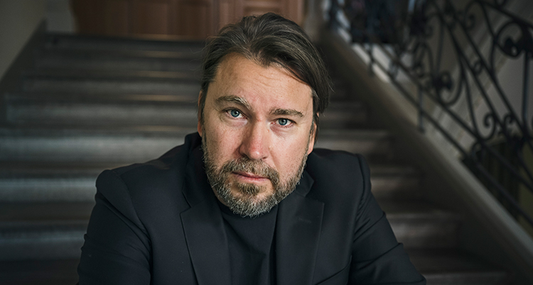 EN man i mörk kostym tittar in i kameran.