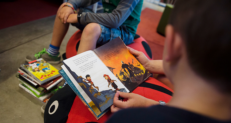 Barn läser böcker på ett bibliotek.