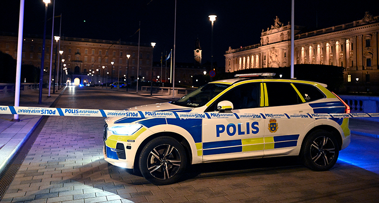 En polisbil är parkerad vid polisernas band. Bakom syns riksdagen och kungliga slottet.