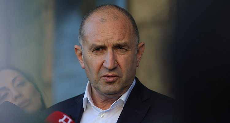 Han pratar i en mikrofon. Han är allvarlig.