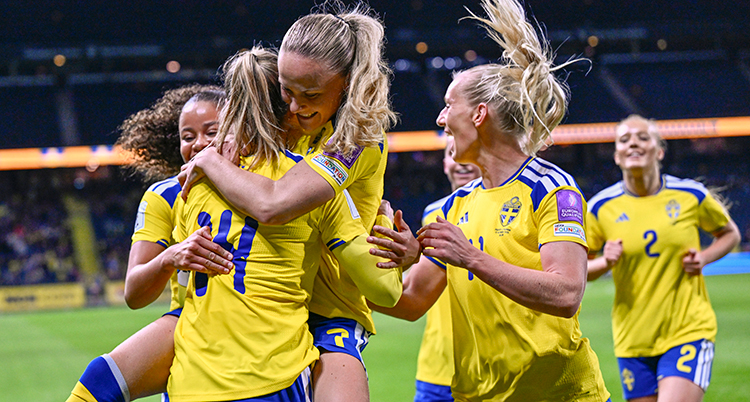 En av spelarna har hoppat upp i famnen på sin lagkamrat. Runt dem jublar de andra spelarna.