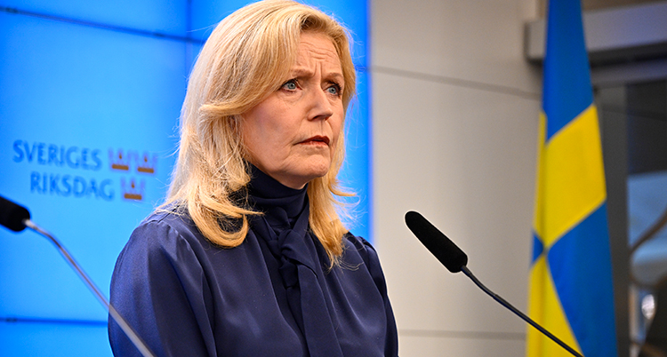 Elisabeth Thand Ringqvist i mörka kläder framför en mikrofon.