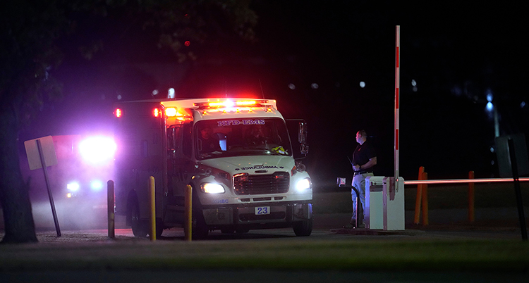 En ambulans med varningslamporna på står vid en gräsmatta på natten i USA.