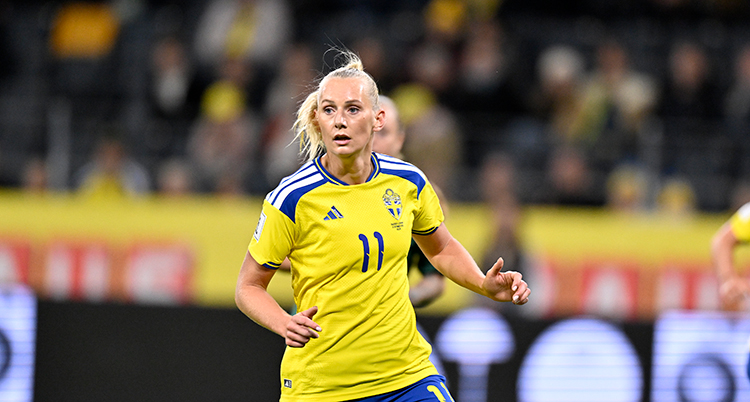 Hon har en tröja med nummer elva. Hon ser fokuserad ut.
